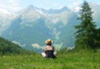 Woman sitting in field looking at mountain