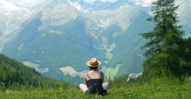 Woman sitting in field looking at mountain